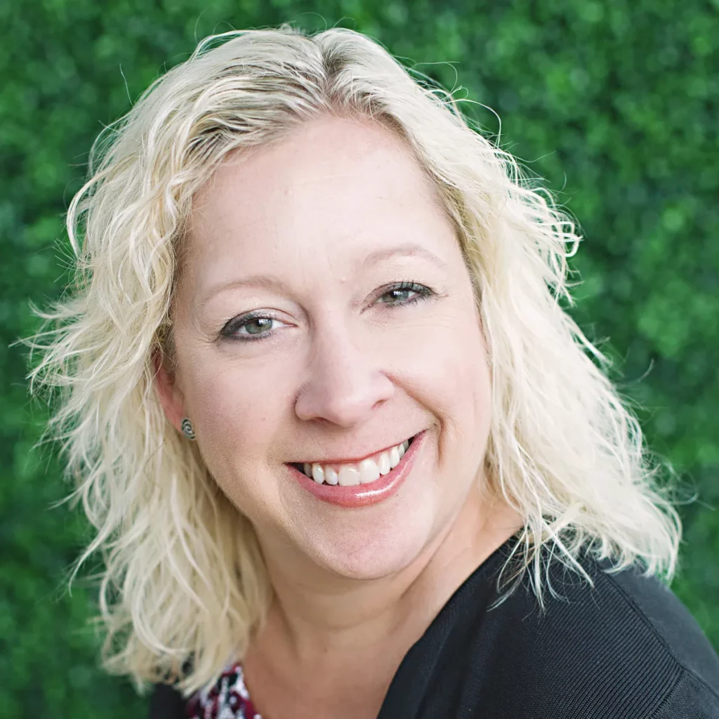 a woman with blonde hair smiling at the camera